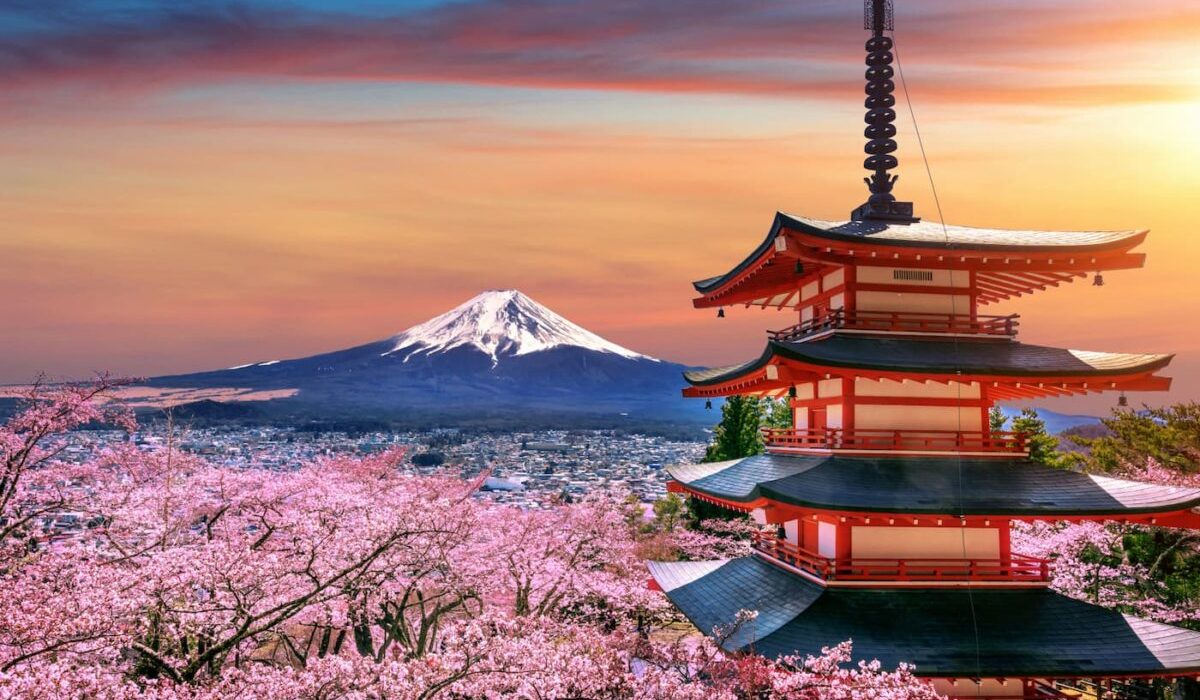 Une haute tour japonaise sur fond de mégalopole et de montagnes.