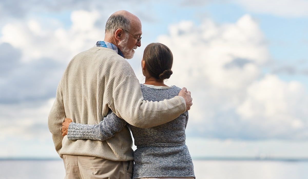 An elderly couple stands on the shore in Indonesia